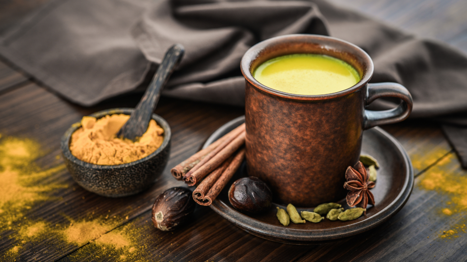 Traditional Indian drink turmeric milk is golden milk with cinnamon, cloves, pepper and turmeric on a wooden background with spices to get good sleep