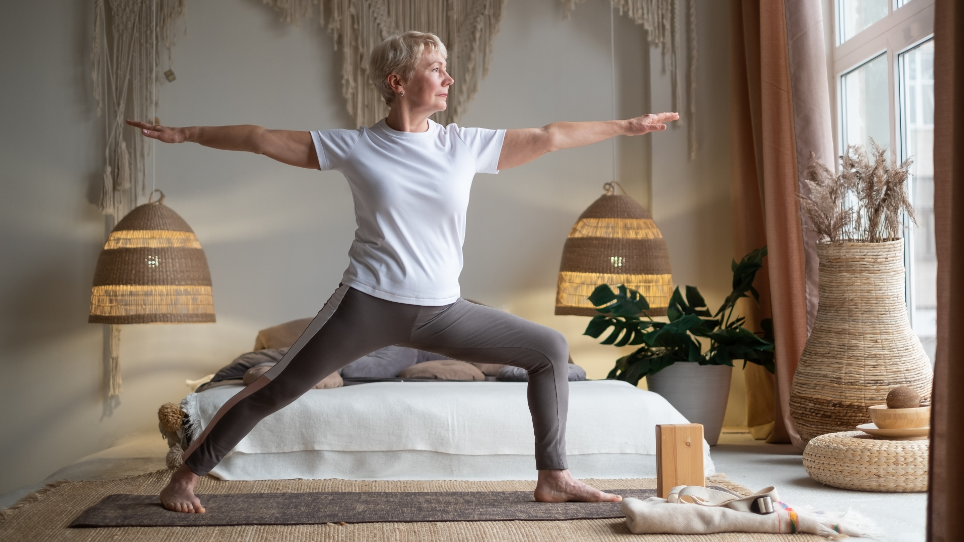 Senior woman practicing yoga, standing in Warrior ll Pose or Virabhadrasana II Pose, a bone-strengthening pose to help prevent osteoporosis.