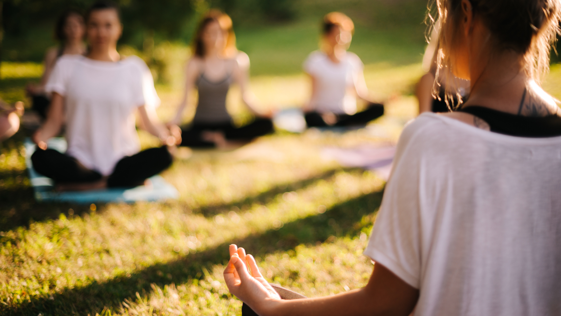 Group of young sporty woman practicing yoga lesson with instructor, sitting in Lotus Pose.