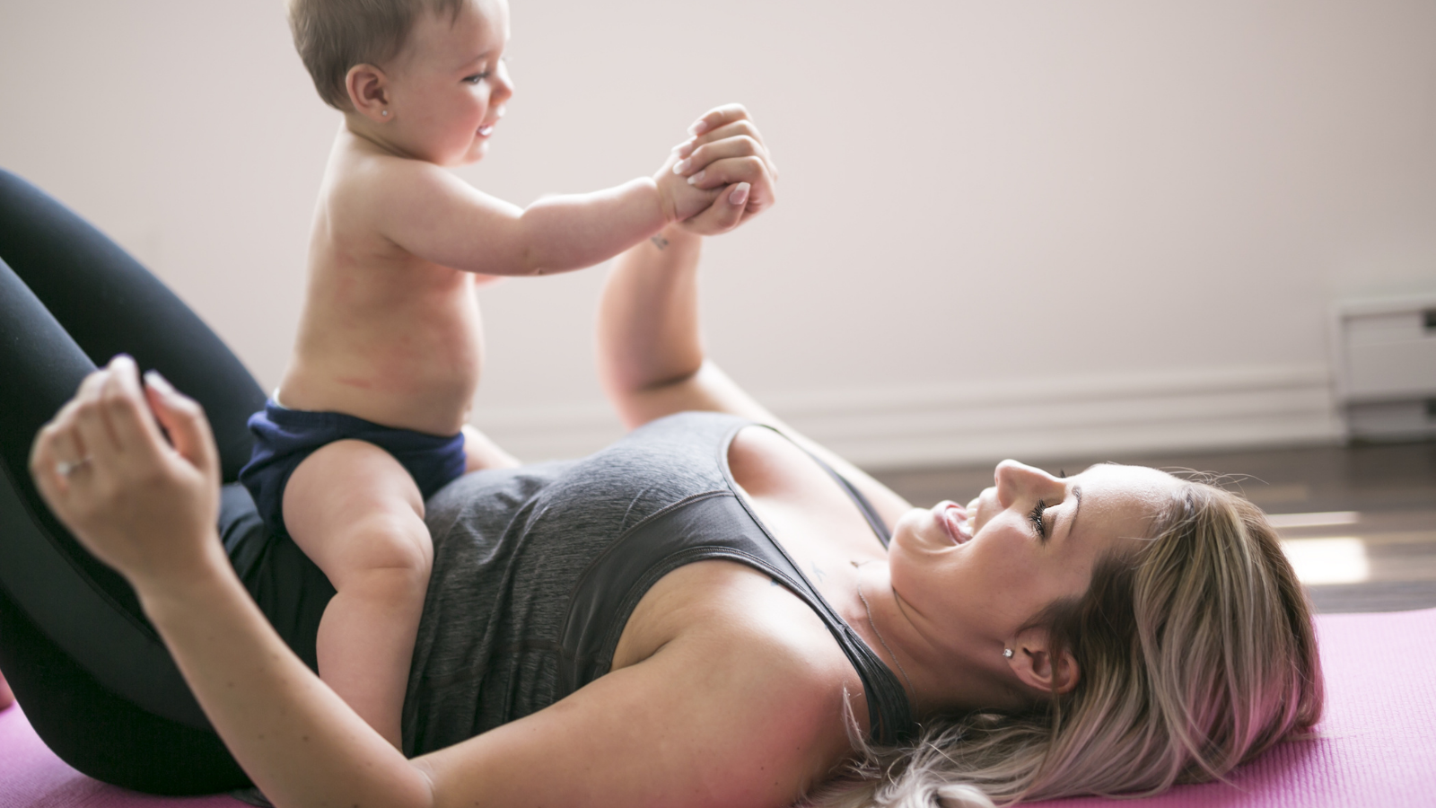 A young mother does physical yoga exercises together with her baby