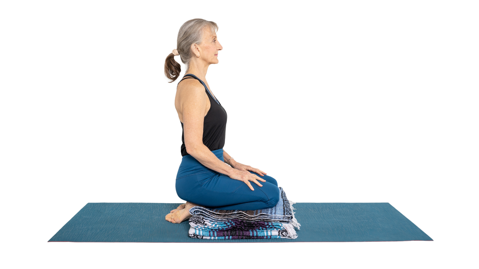 Woman sitting in Hero's Pose or Virasana to work on facial exercises in a yoga sequence for TMJ pain