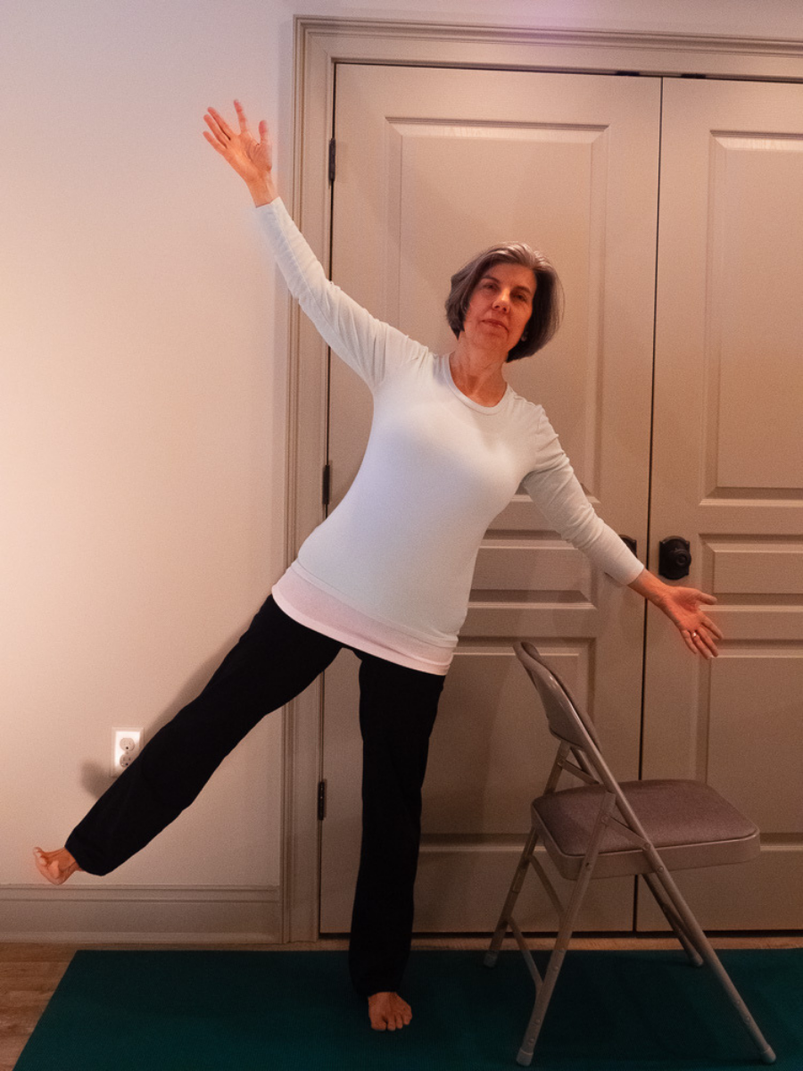 Balancing Star is a beginner-friendly balance pose shown here with practitioner using a chair for extra support if needed.